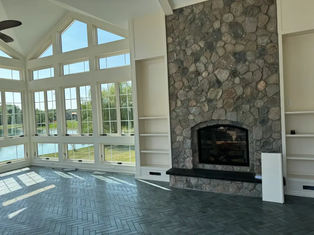 Great room with a full-height river rock fireplace framing water views